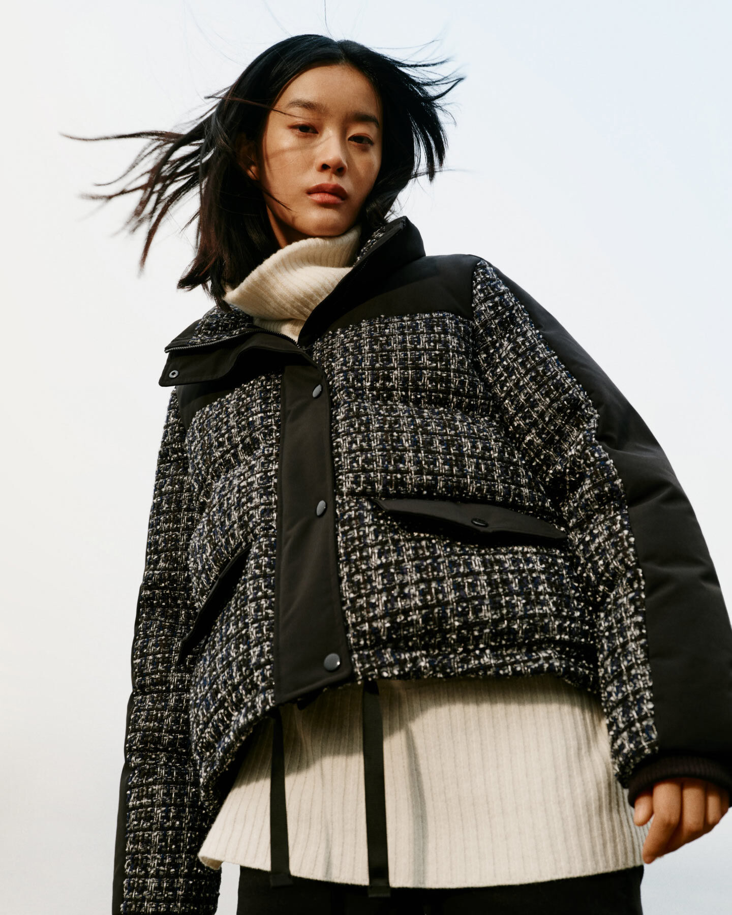 Woman wearing Tweed Down Jacket in black and Lounge Rollneck Sweater in color cream. 